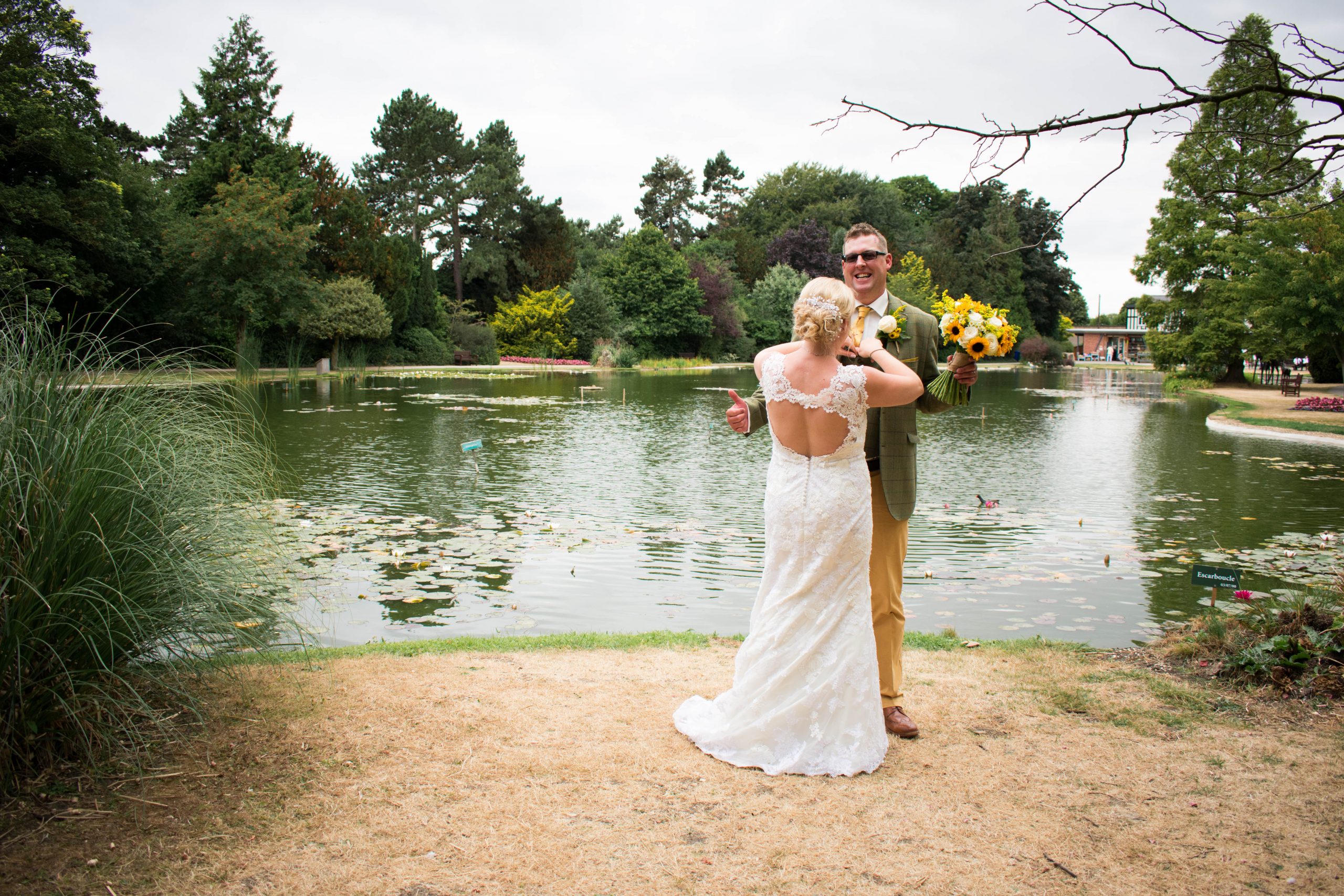 Bride and groom with summer wedding flowers standing next to lake at Burnby Hall Gardens in Pocklington, East Riding of Yorkshire