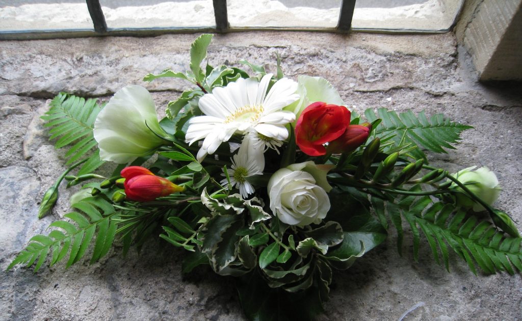 Red and white wedding flower arrangement on stone window ledge at York hospitium